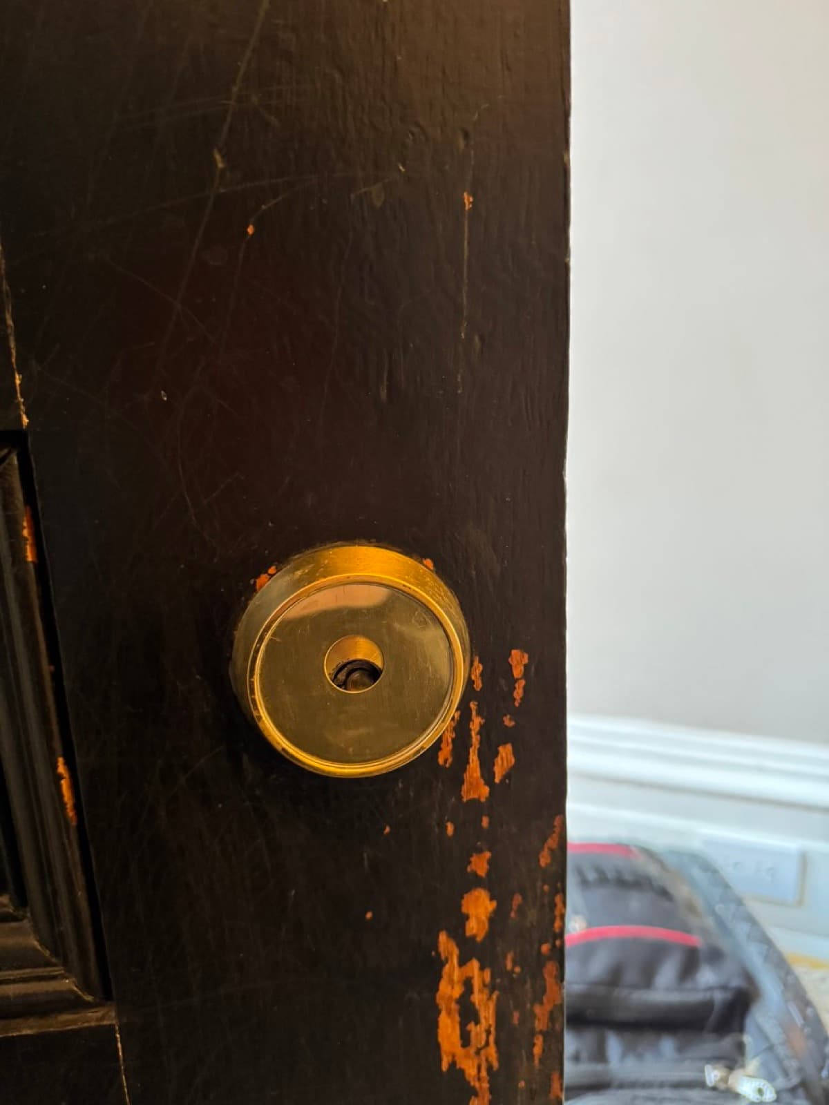 Brass mortise cylinder on a black Brooklyn door — our work, not stock
